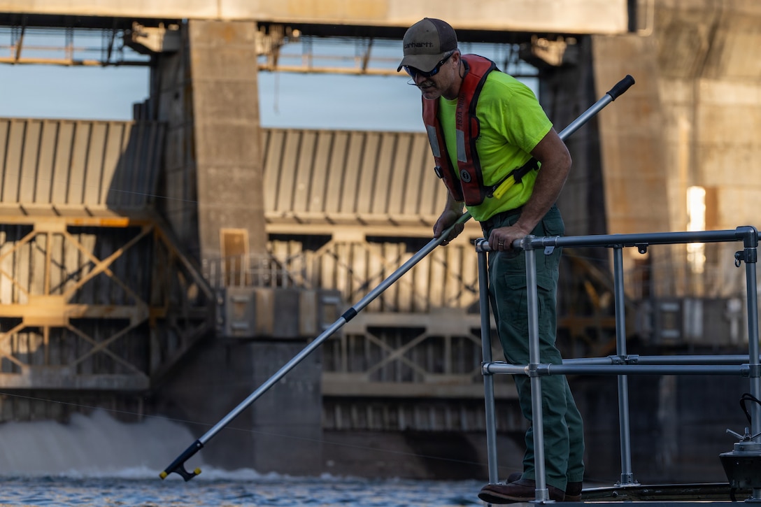 Picture of a man using a pole to grab a sampling device.