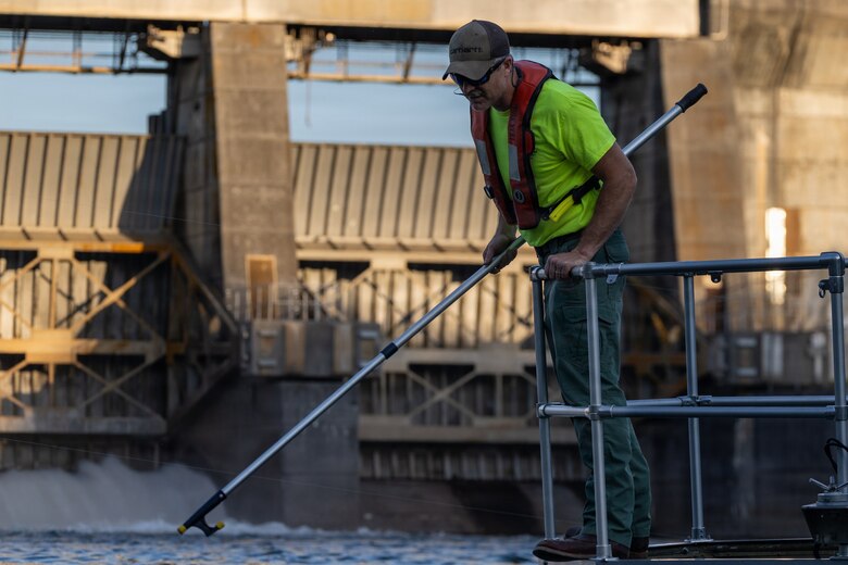 Picture of a man using a pole to grab a sampling device.