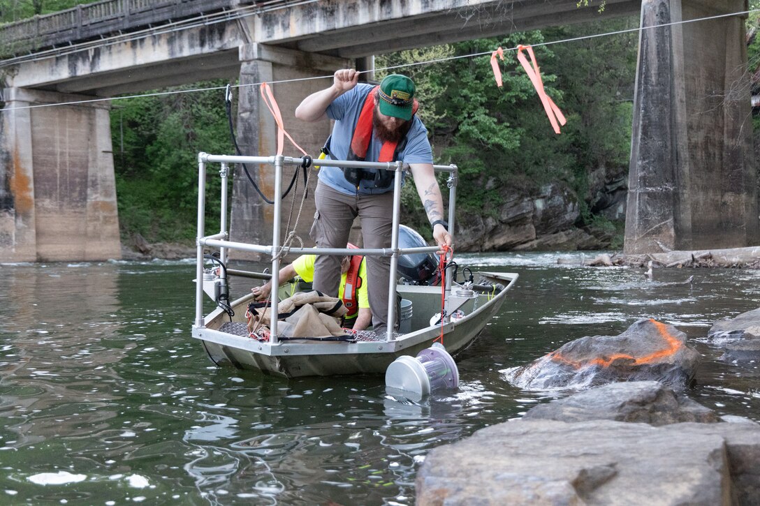 Picture of a man in a boat by a bridge.