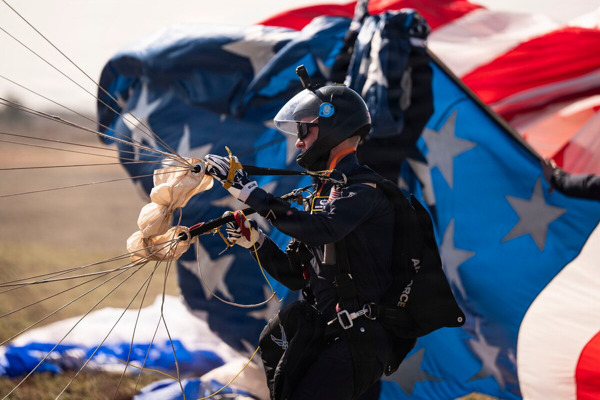 U.S. Air Force Academy Cadet Carter Beswick, a Wings of Blue parachutist, adjusts his gear after a demonstration jump from a Texas Air National Guard HC-130 Combat King II during the Feria Internacional del Aire y del Espacio (FIDAE) in Santiago, Chile, April 11, 2026. The Wings of Blue serve as ambassadors of the U.S. Air Force, building international relationships and inspiring future generations through aerial demonstration and engagement at events like FIDAE. (U.S. Air Force photo by Airman 1st Class Samantha Melecio)