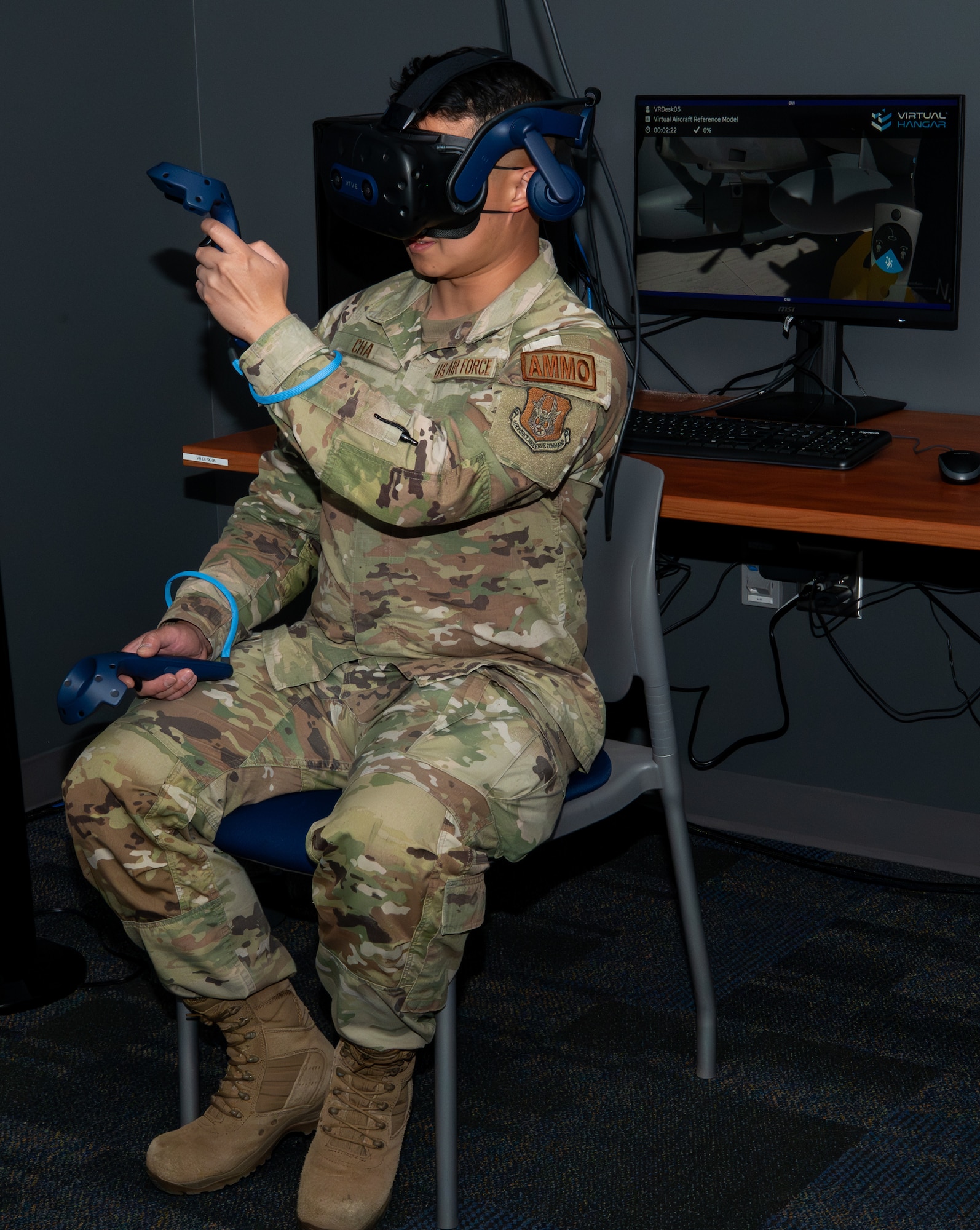 A military member holding a controller in each hand while wearing a VR headset.