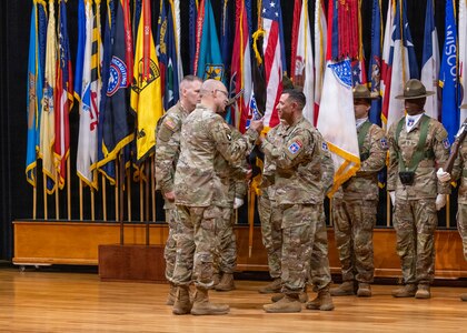 Command Sgt. Maj. Shade S. Munday, outgoing command sergeant major of U.S. Army Recruiting Command, passes the command colors to Lt. Gen. Johnny K. Davis, commanding general of U.S. Army Recruiting Command, during a change of responsibility ceremony at Waybur Theater, Fort Knox, Kentucky, April 17, 2026.