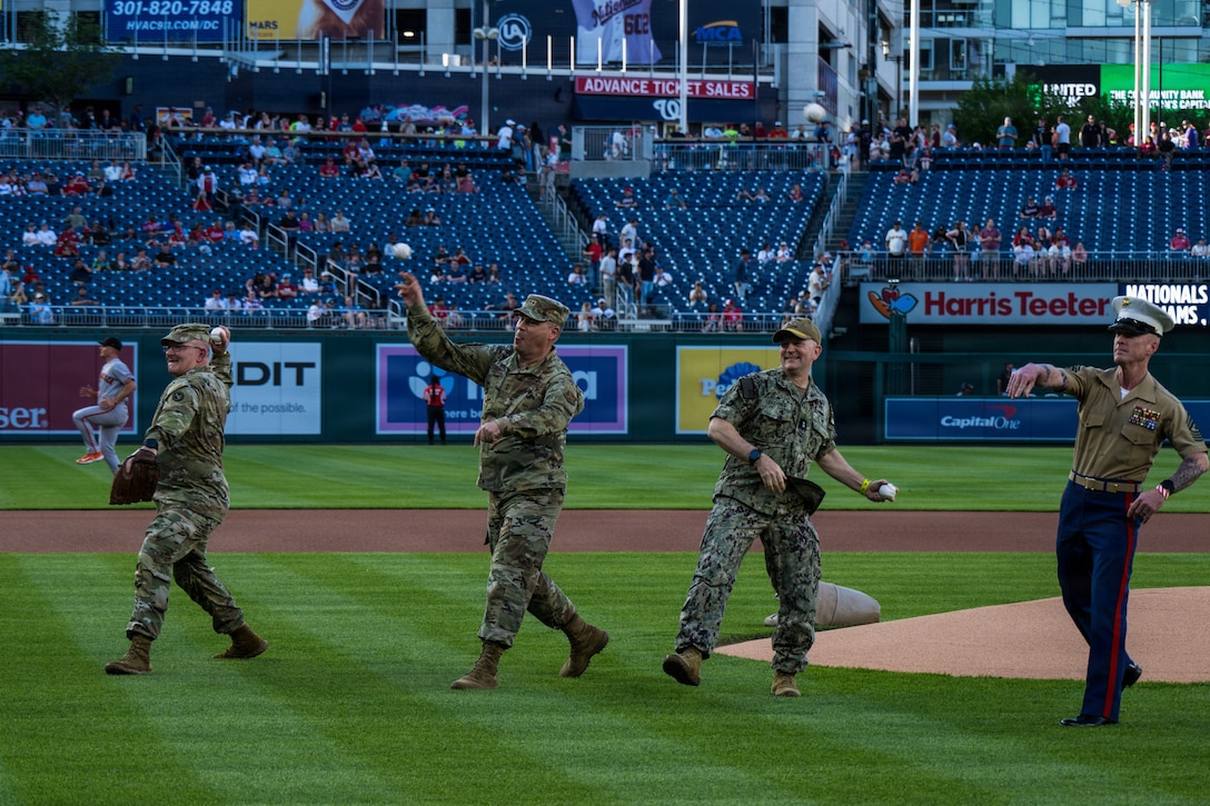 service members throw the first pitch on the feild.