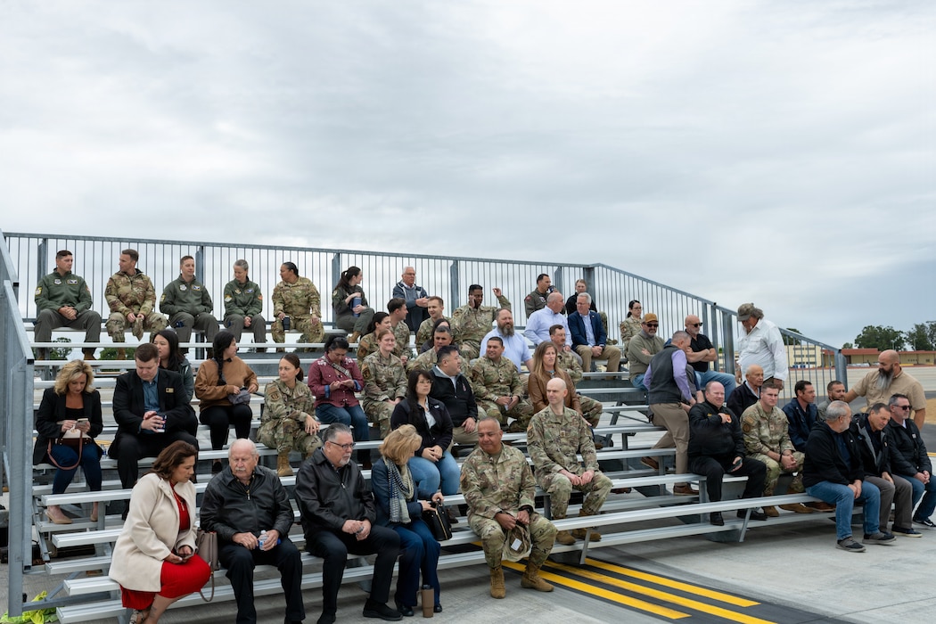 Attendees waiting on bleachers for an aircraft to land on newly opening runway.