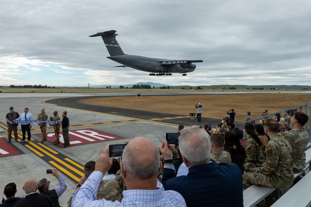 Crowd photographing an aircraft prepare to land on newly opened runway from bleachers