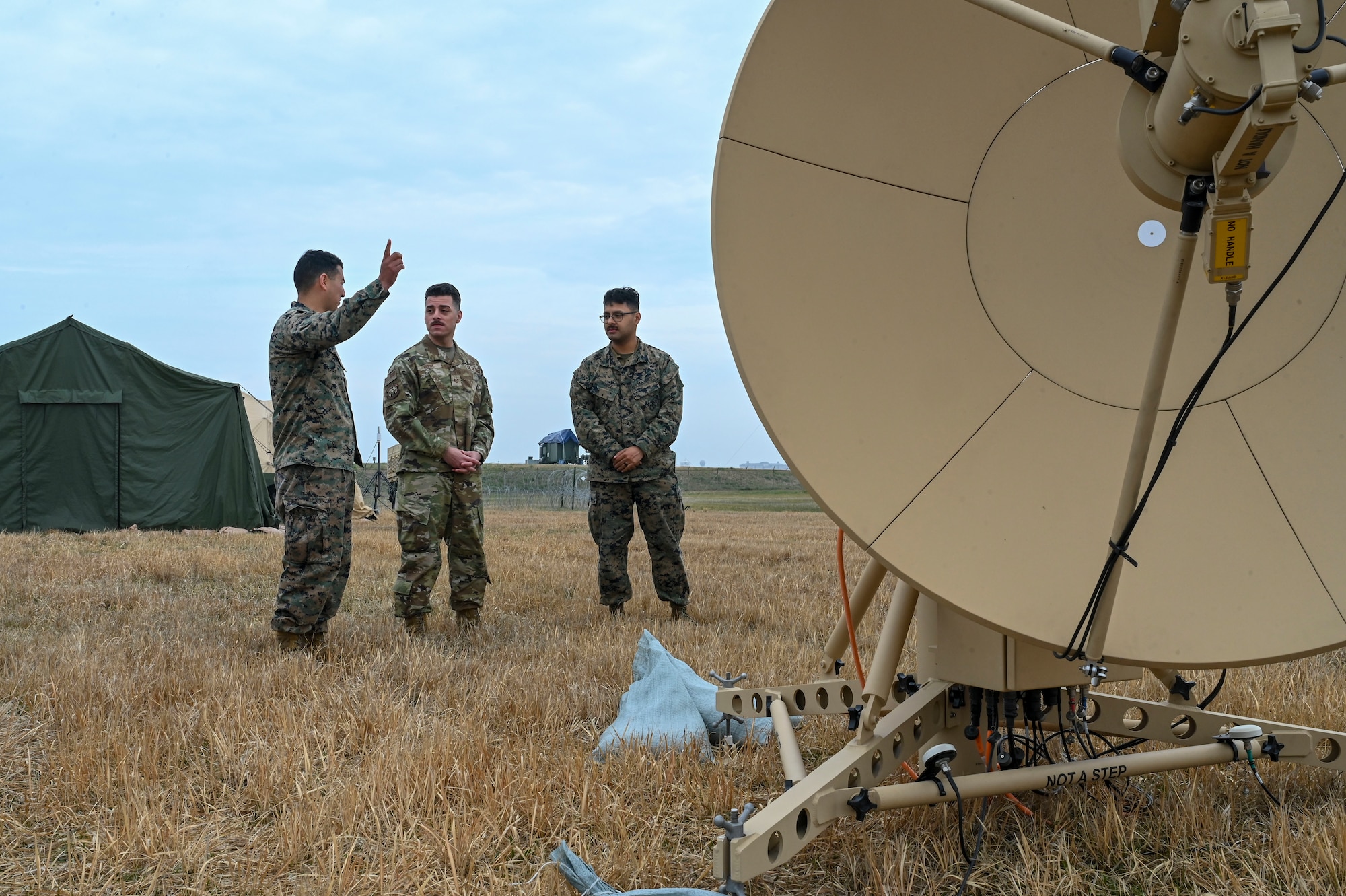 A group of men look at a satellite dish.
