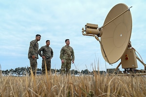 A group of men look at a satellite dish.