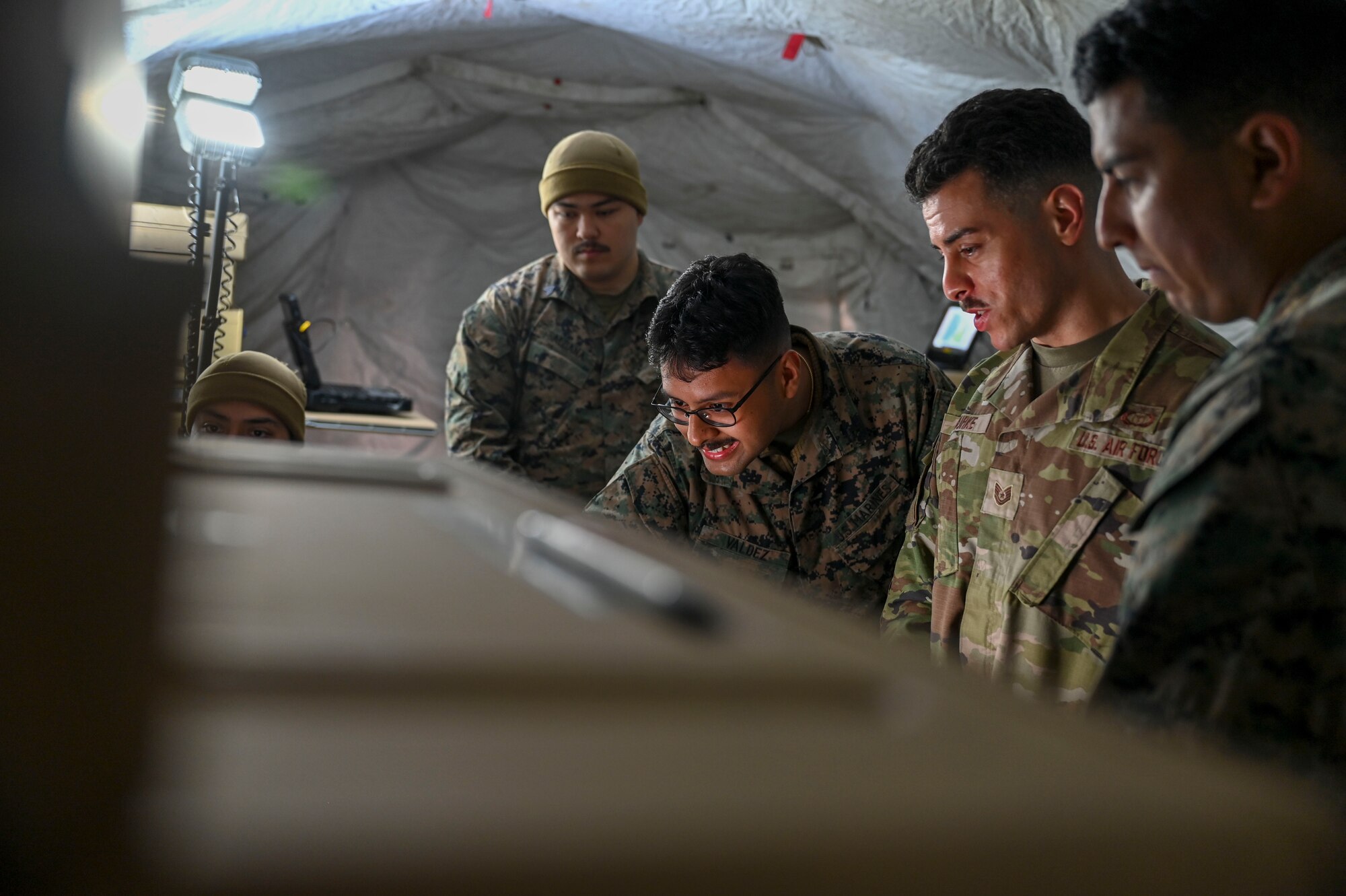 A group of men look at a computer.