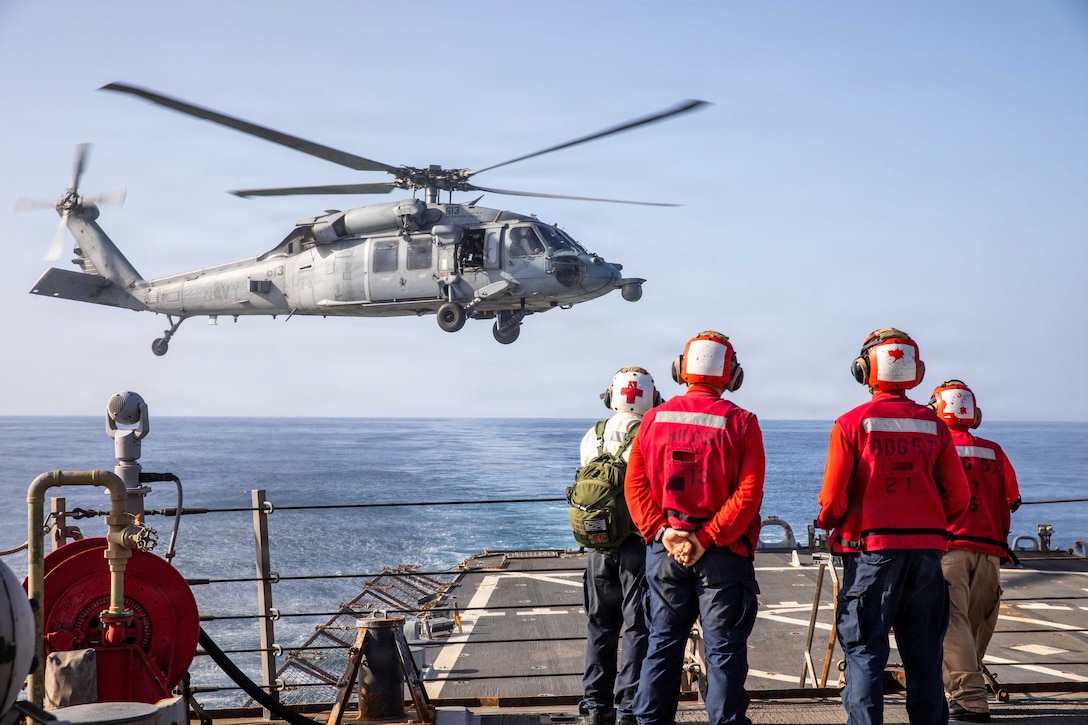 U.S. Sailors assigned to the Arleigh Burke-class guided-missile destroyer USS Mitscher (DDG 57), observe a MH-60S Sea Hawk helicopter, attached to Helicopter Sea Combat Squadron (HSC) 14, April 16, 2026. (U.S. Navy Photo)
