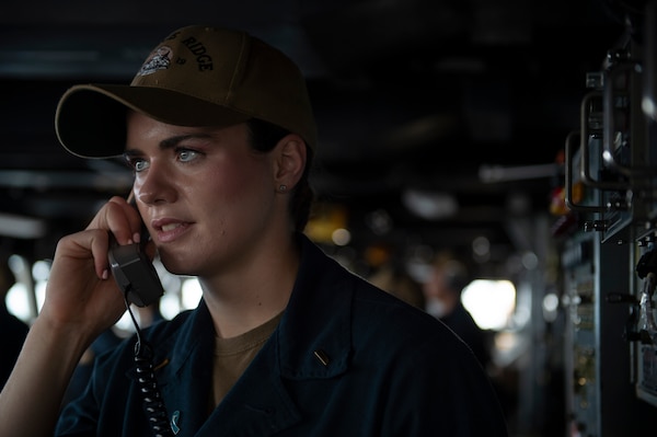 Ensign Shannon Clancy communicates over the bridge phone aboard U.S. 7th Fleet flagship USS Blue Ridge (LCC 19) as the ship departs White Beach Naval Facility in Okinawa, Japan, April 21, 2026.