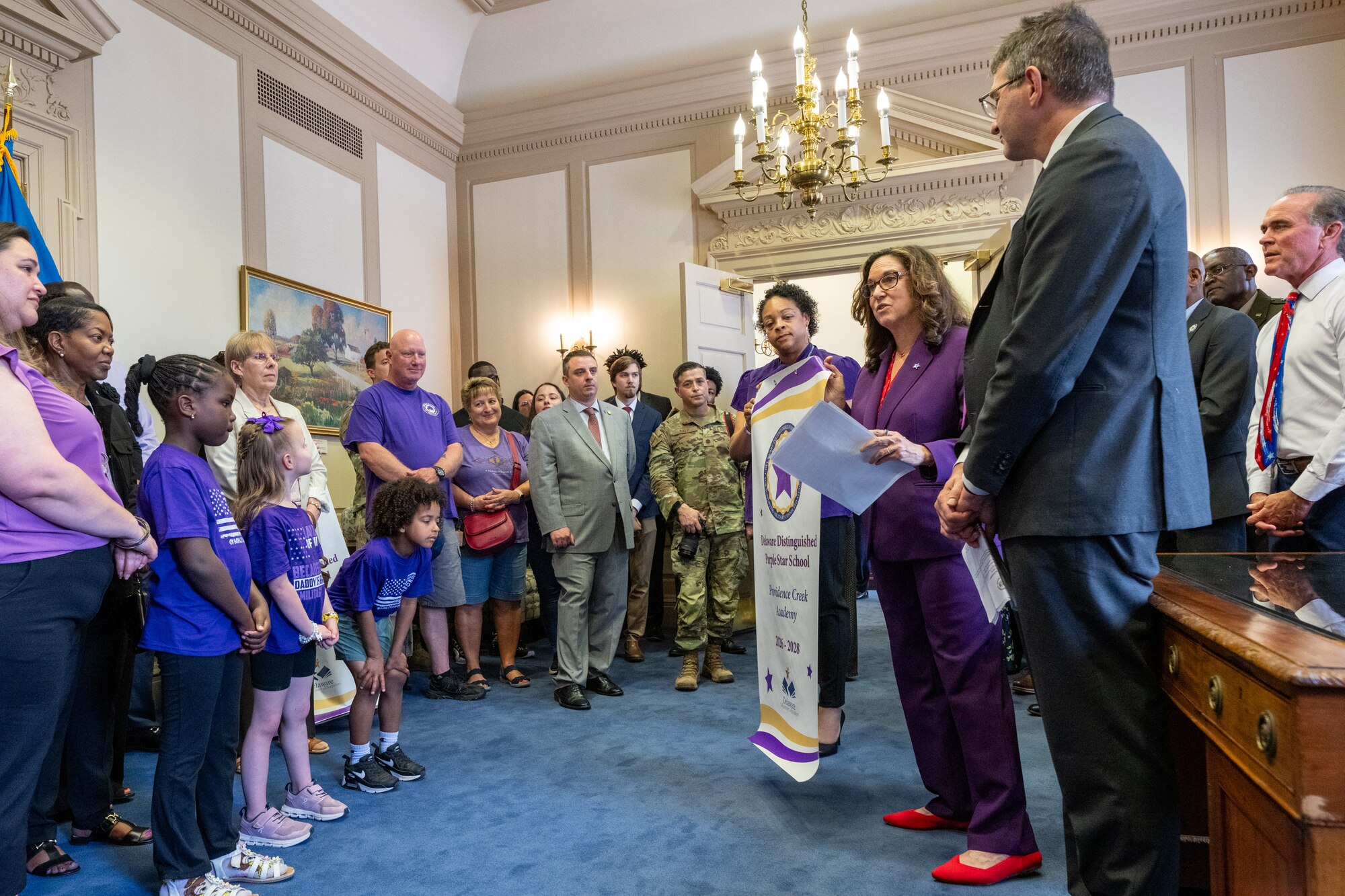Delaware Gov. Matt Meyer and Cindy Marten, Del. Secretary of Education, present a banner recognizing Providence Creek Academy as a Purple Star School before signing a document proclaiming April as the Month of the Military Child in Dover, Delaware, April 16, 2026. The Purple Star School program is a designation for military friendly schools and requires special staff training, dedication military liaisons and programs to aid students with duty station transitions. (U.S. Air Force photo by Mauricio Campino)