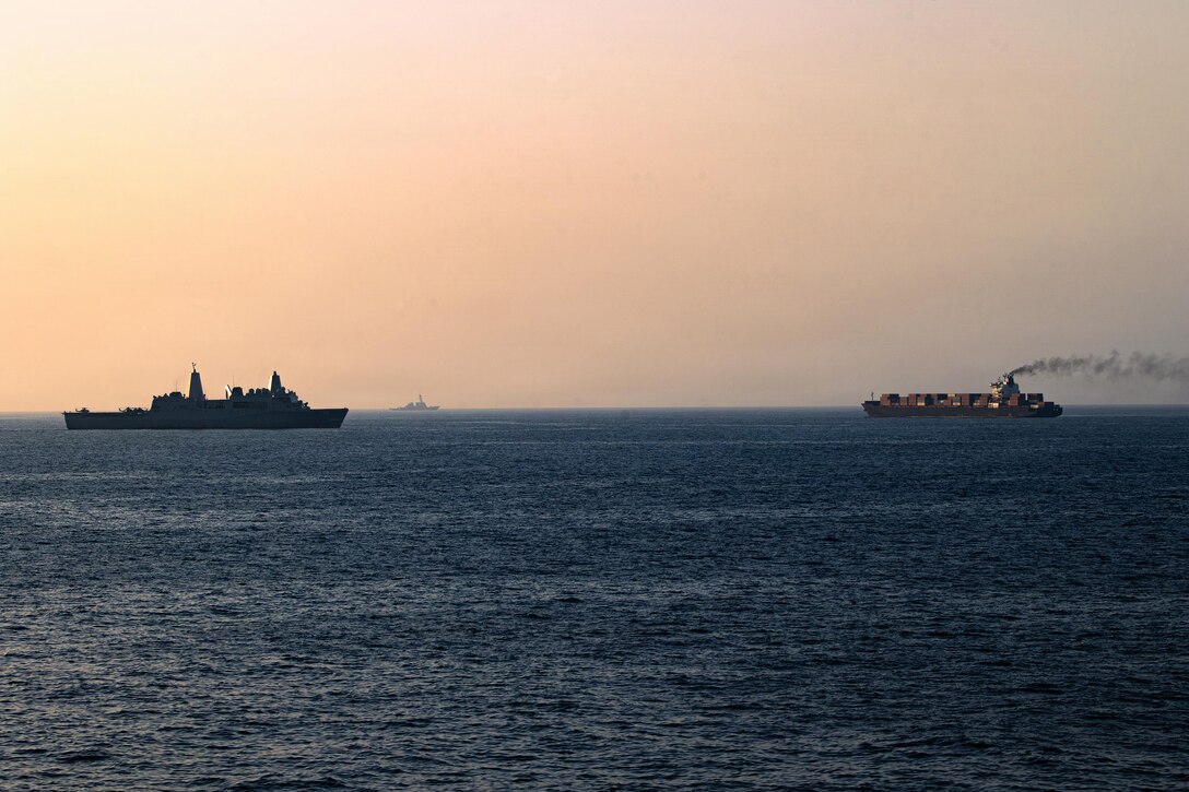 Orangish sky frames two ships operating in water, with a third in the far distance.