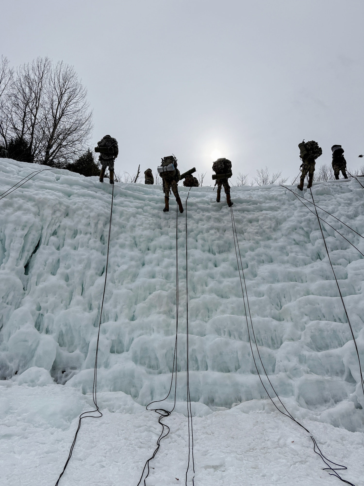 image of military personnel rappelling down an ice wall.