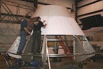 Mark Melendez (left), a mechanical engineer at Naval Surface Warfare Center, Carderock Division, works on fabrication of an Orion capsule test article known as JENOM (Neutral Buoyancy Lab Mockup)