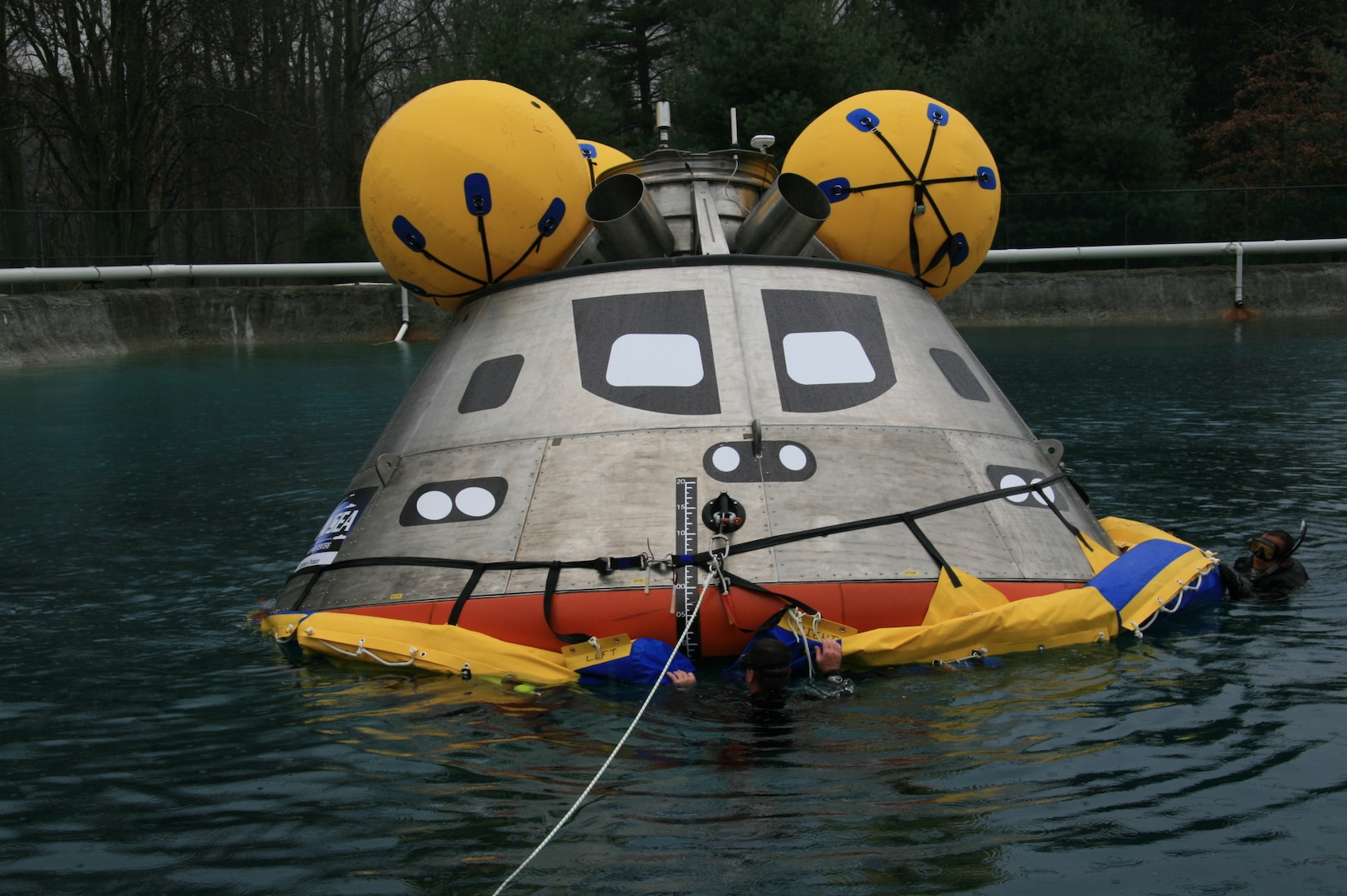 A full-scale Orion capsule test article is evaluated in the Carderock test pond during early recovery testing.