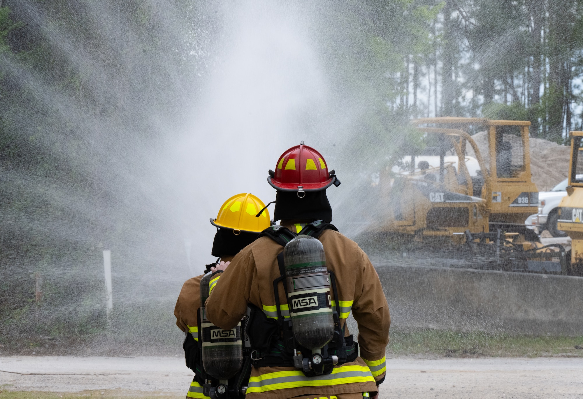 Firefighters test fire hose pressure in full gear.