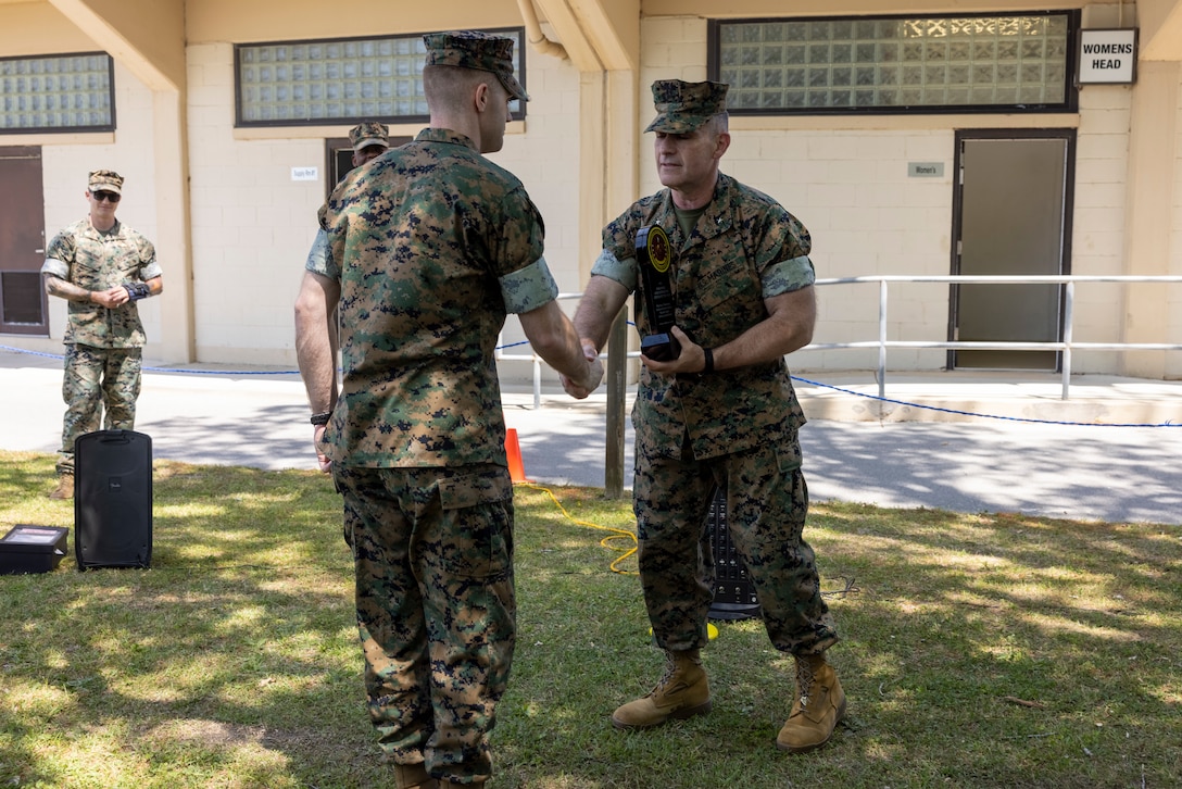 U.S. Marine Corps Brig. Gen. Ralph J. Rizzo, Jr., right, commanding general, Marine Corps Installations East-Marine Corps Base(MCIEAST-MCB) Camp Lejeune, presents the 2025 Personnel Administration Center of the Year Award to a Marine with the MCB Camp Lejeune Regional Personnel Administration Center (RPAC), at MCB Camp Lejeune, North Carolina, April 16, 2026. MCIEAST RPAC won this award for its efficient and accurate administrative, pay, and reporting support across multiple installations, ensuring that Marines' records were properly maintained and they remained ready for worldwide deployment. (U.S. Marine Corps photo by Cpl. Jessica J. Mazzamuto)