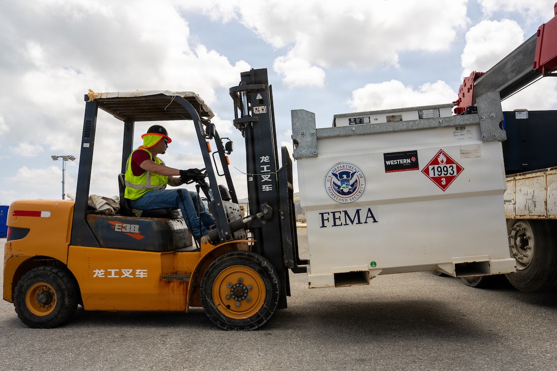 a fork lift operator uses a forklift to maneuver a large fuel tank.