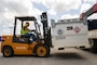 a fork lift operator uses a forklift to maneuver a large fuel tank.