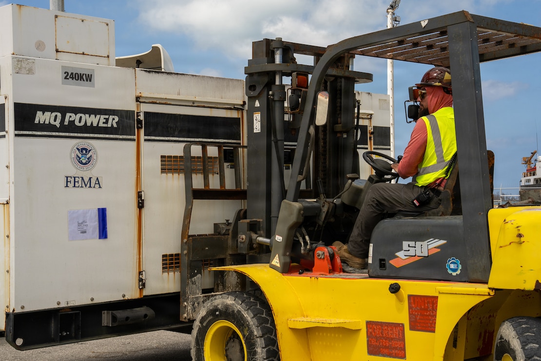 a forklift operator uses a forklift to move a large generator.