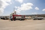Two flatbed trucks are loaded with generators at a port in Saipan