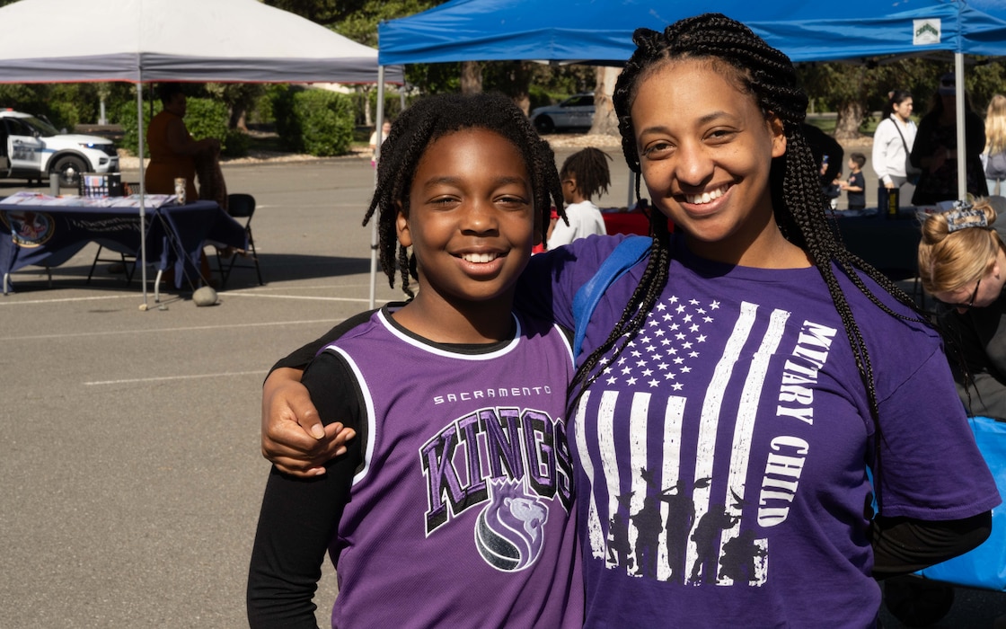 A mother poses with her son, they are both wearing matching purple shirts.