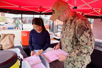 Hospitalman Apprentice Wilson Current (right) inspects a new vendor at the 29 Palms Farmers Market at Marine Corps Air Ground Combat Center (MCAGCC), April 9, 2026. Preventive medicine technicians ensure vendors comply with Navy and Department of War food safety standards, supporting the health and readiness of service members and their families. (U.S. Navy photo by Christopher Jones, NMRTC/NH Twentynine Palms public affairs officer)