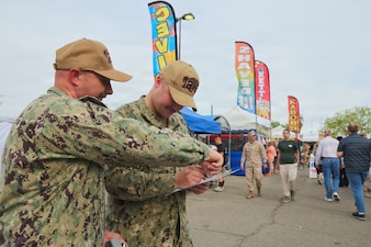 Hospital Corpsman 1st Class Sean Weimer (left) and Hospitalman Apprentice Wilson Current conduct food safety inspections at the 29 Palms Farmers Market at Marine Corps Air Ground Combat Center (MCAGCC), April 9, 2026. Preventive medicine technicians ensure vendors comply with Navy and Department of War food safety standards, supporting the health and readiness of service members and their families. (U.S. Navy photo by Christopher Jones, NMRTC/NH Twentynine Palms public affairs officer)