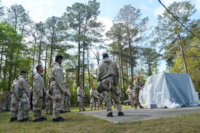 A group of Airmen stand watching another Airman contain an object during training