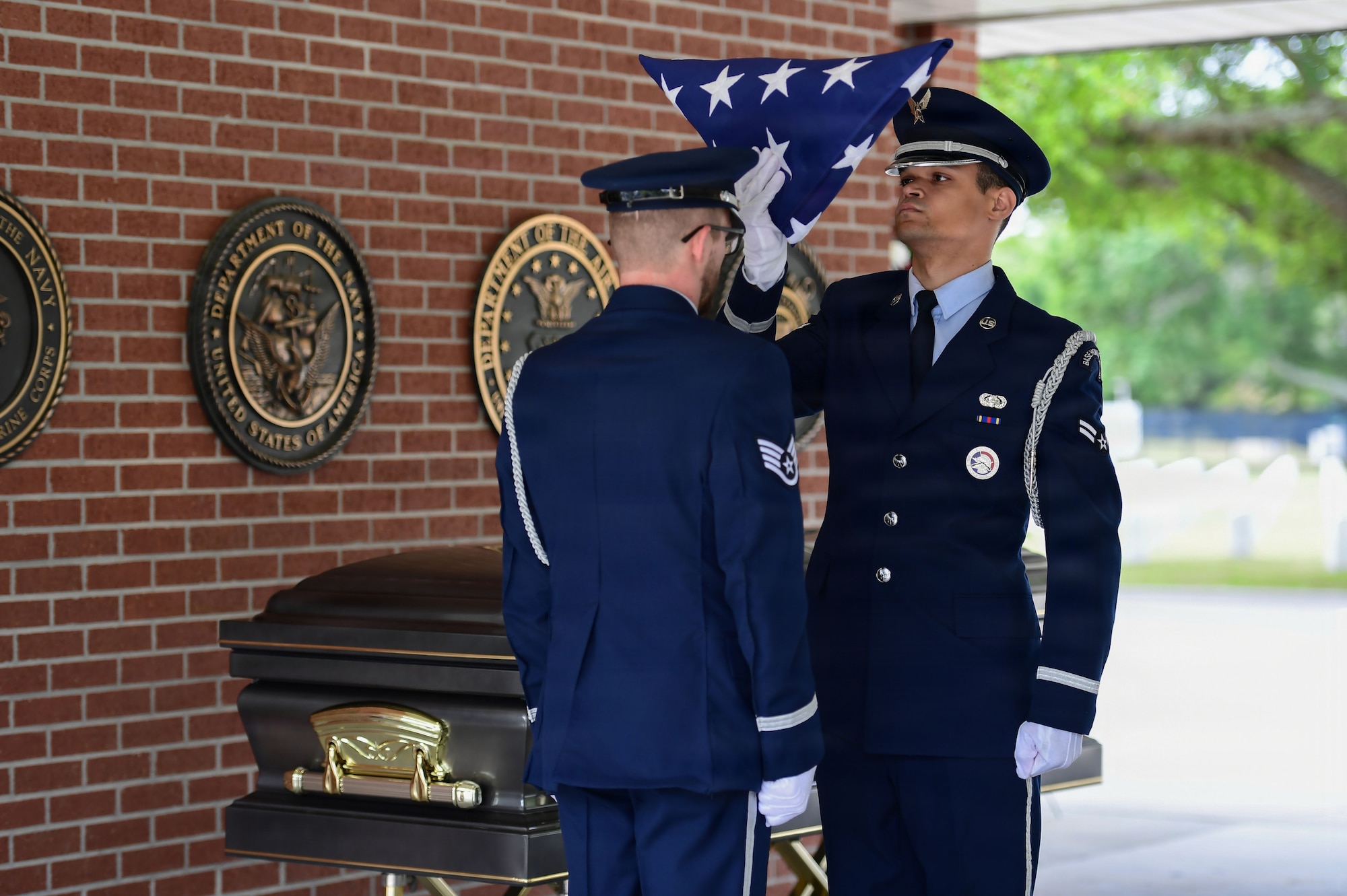 Two military members fold a U.S. flag during a funeral.