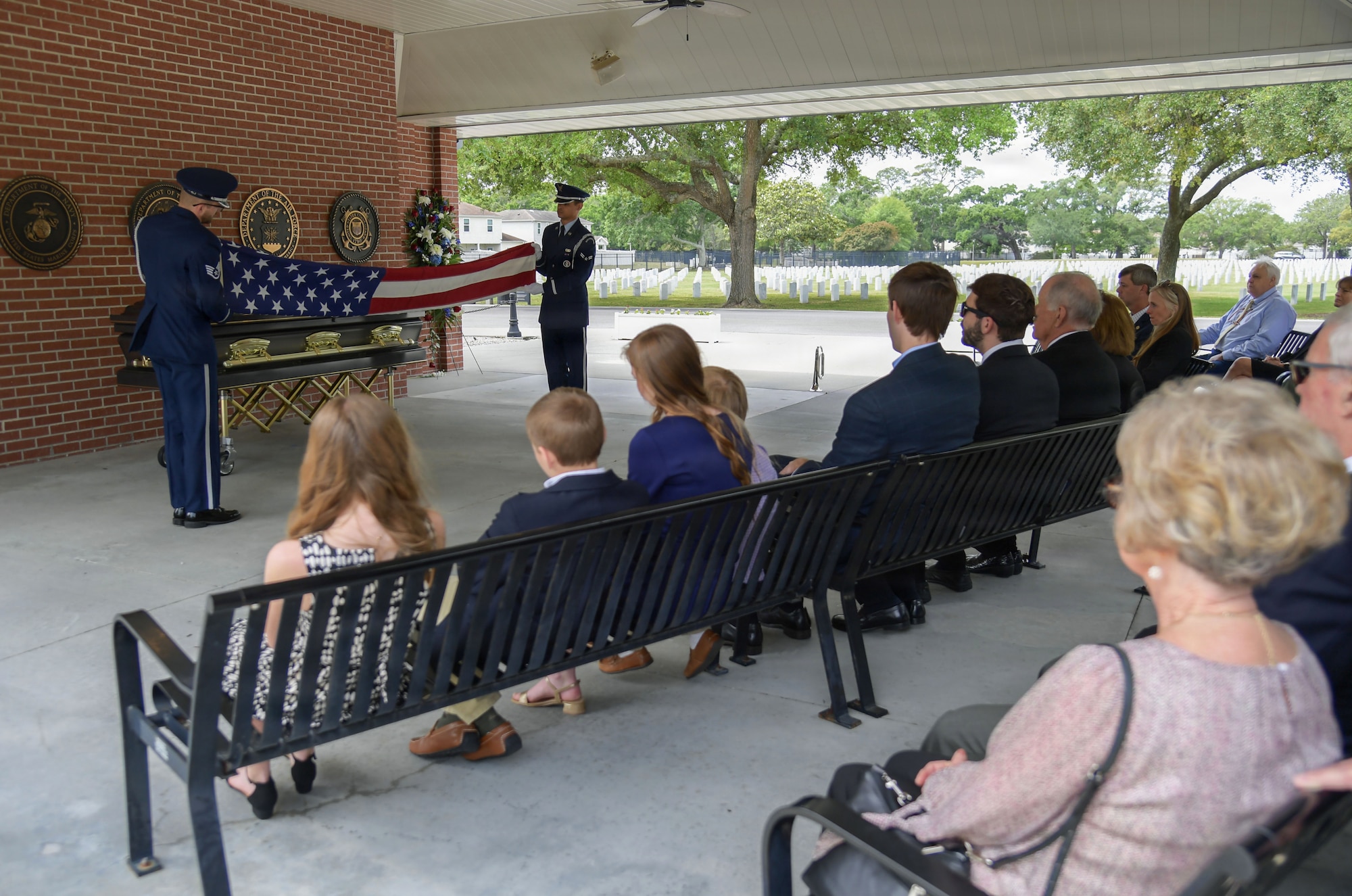 Two military members fold a U.S. flag during a funeral.