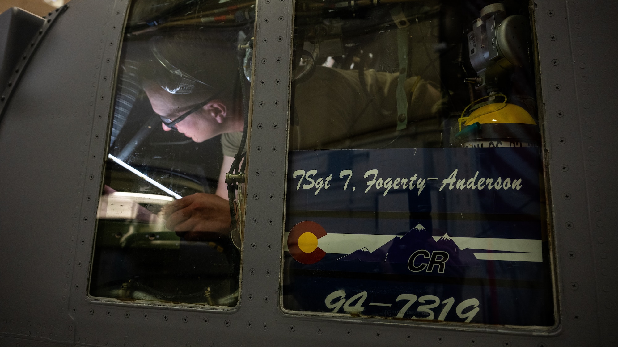 An airman is laying down under the flight controls of the C-130H Hercules aircraft performing an inspection.