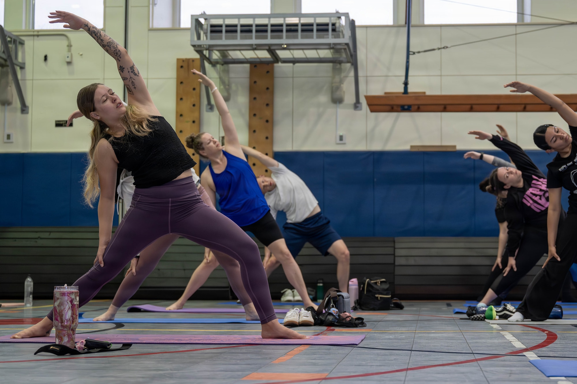 Service members and civilians do yoga.