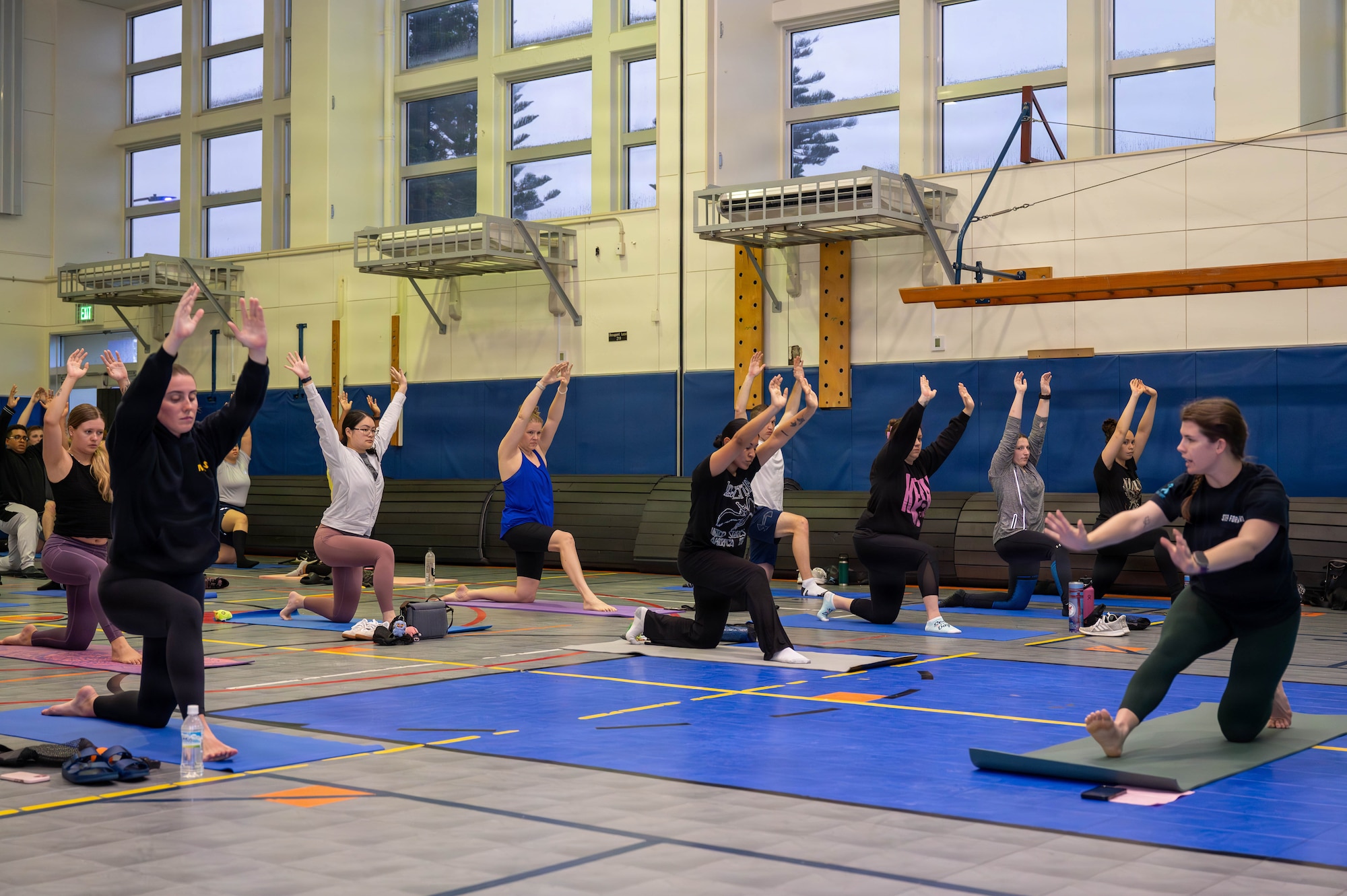 Service members and civilians do yoga.