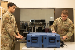 Airmen 1st Class Elijah Hubble and Owen Gettings, 412th Communications Squadron, prepare to deploy flyaway kits during a readiness exercise at Edwards Air Force Base, California, March XX. The kits are portable servers that enable immediate operations in remote or tactical environments following a cyberattack. (U.S. Air Force photo by Giancarlo Casem)