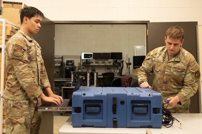 Airmen 1st Class Elijah Hubble and Owen Gettings, 412th Communications Squadron, prepare to deploy flyaway kits during a readiness exercise at Edwards Air Force Base, California, March XX. The kits are portable servers that enable immediate operations in remote or tactical environments following a cyberattack. (U.S. Air Force photo by Giancarlo Casem)