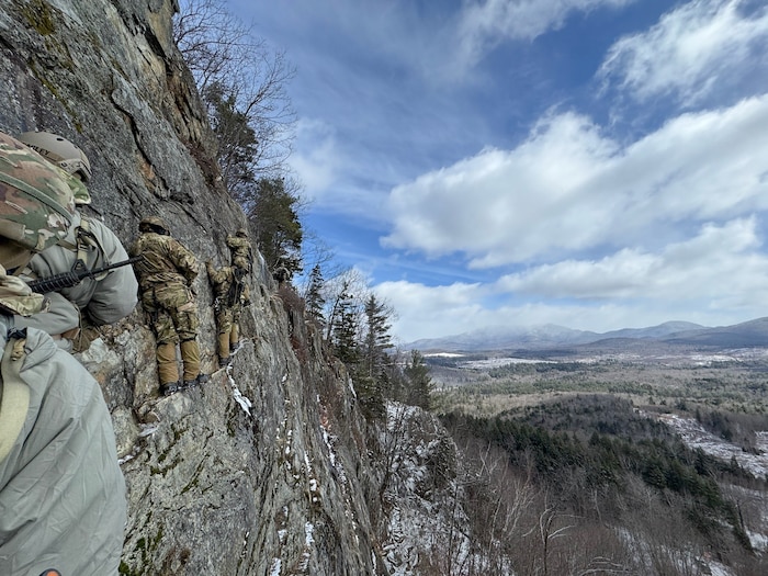 image of military personnel moving across a cliff face.