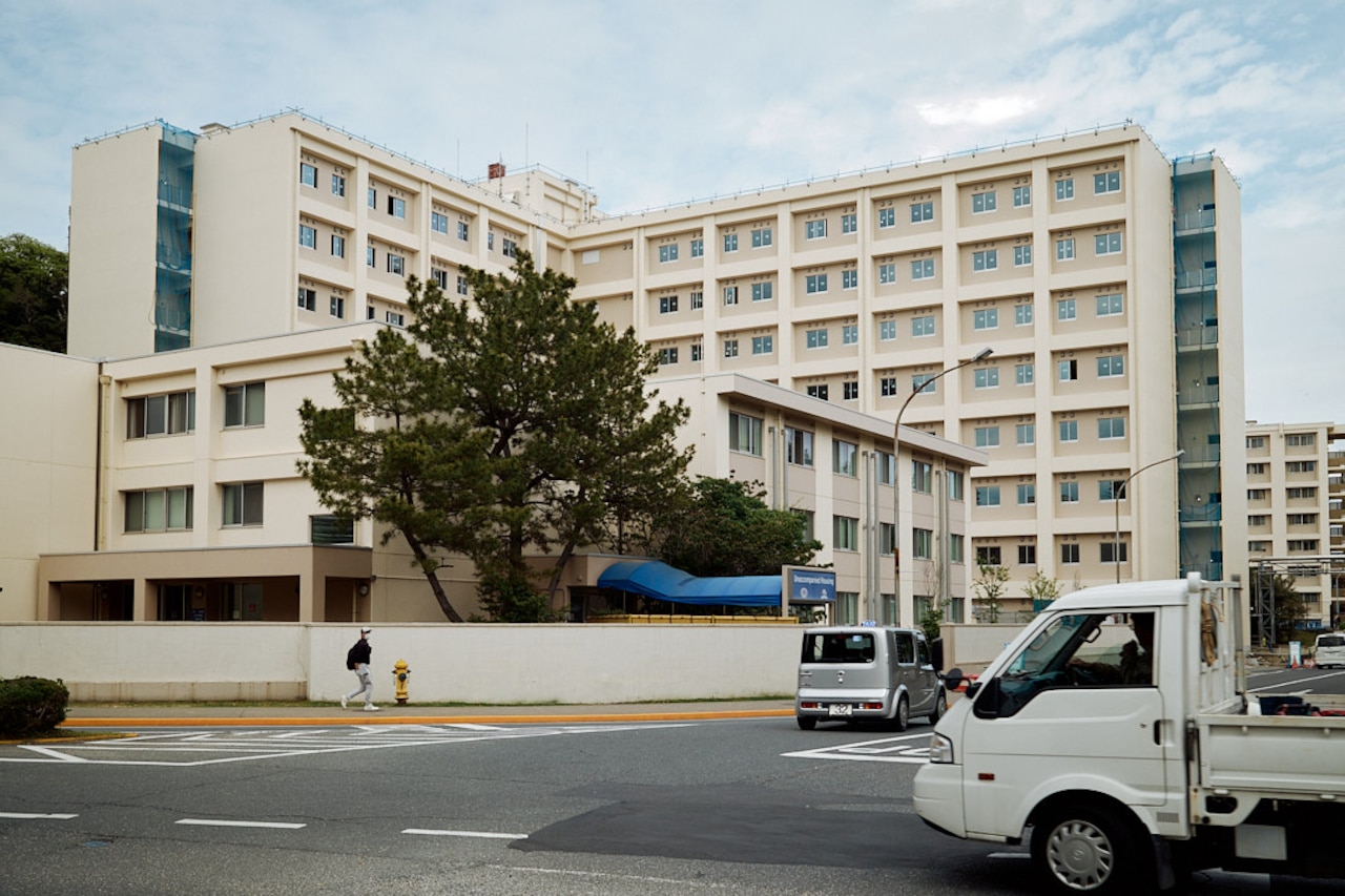 Motor vehicles drive by a newly constructed high-rise residential tower.