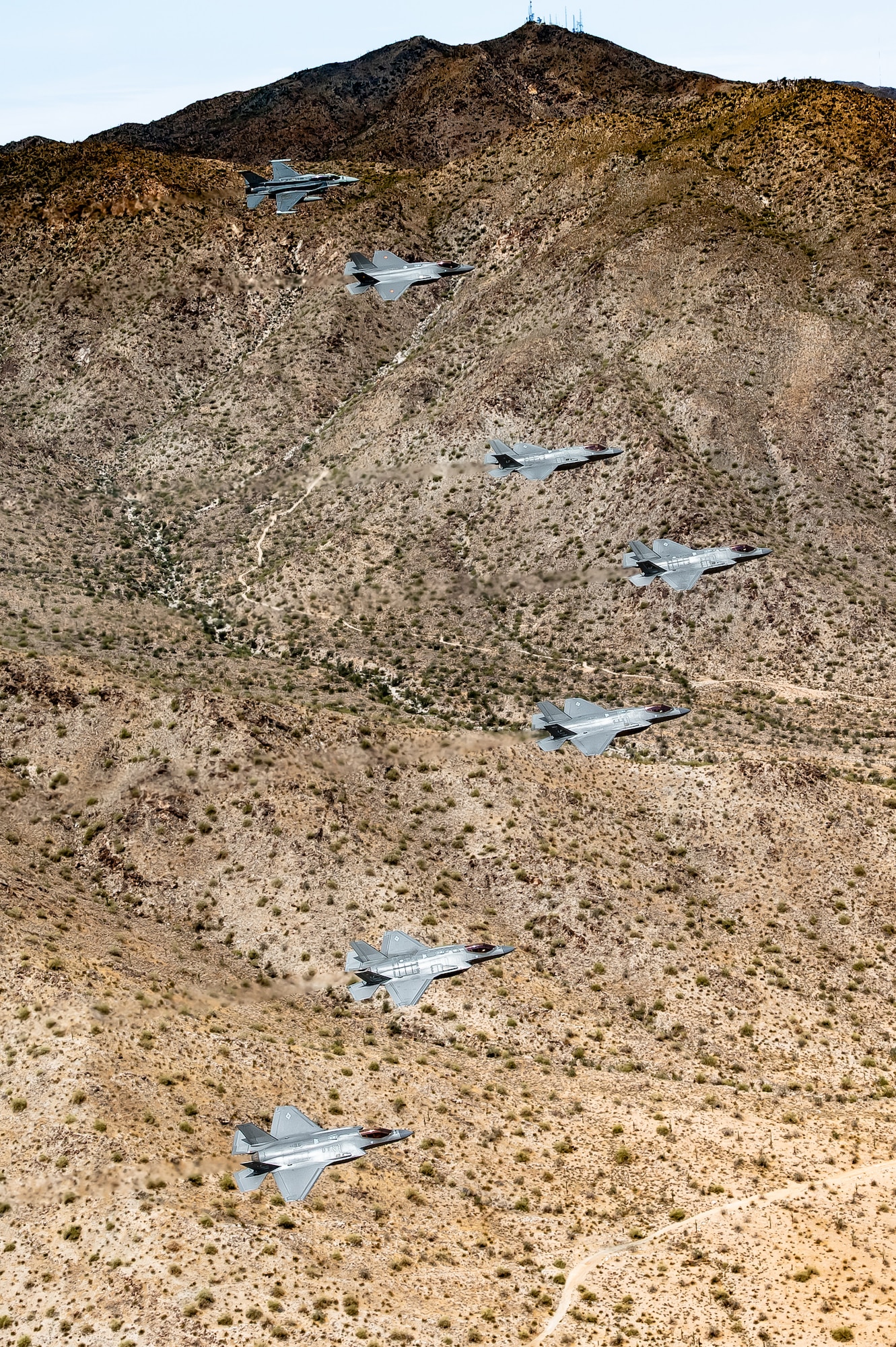 A Republic of Singapore Air Force F-16D Fighting Falcon, a Belgian Air Component F-35A Lightning II, and U.S. Air Force F-35A Lightning II aircraft assigned to the 56th Fighter Wing fly in formation over White Tanks Mountains