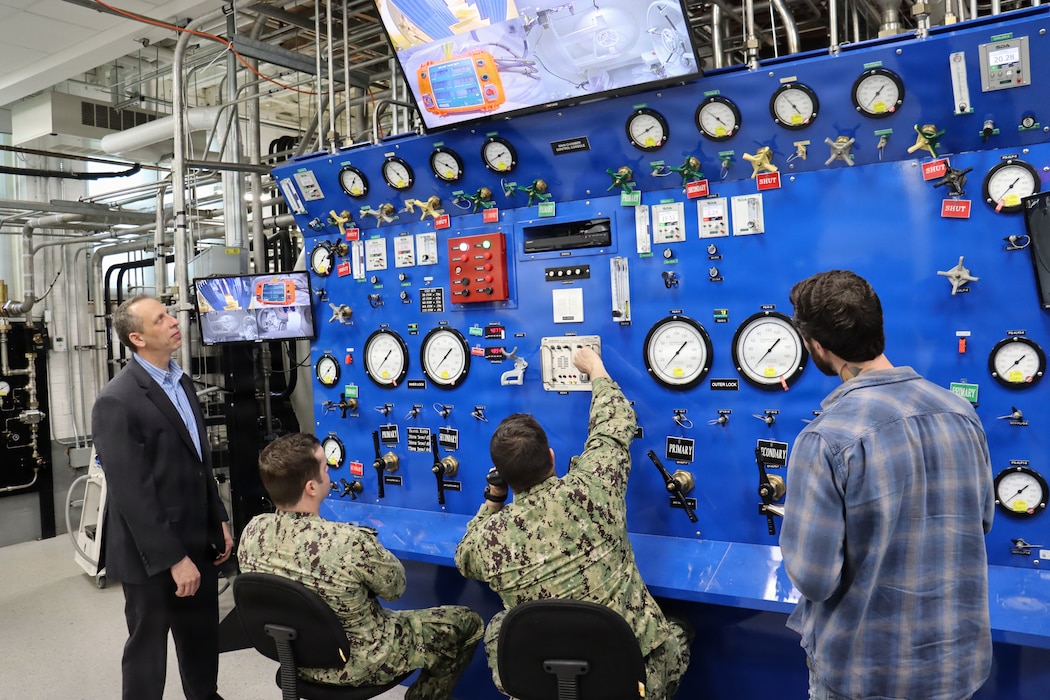 GROTON, Conn (April 21, 2025) Dr. John Florian (left), head of Naval Submarine Medical Research Laboratory’s (NSMRL) Warfighter Health and Protection department, supervises an ongoing research protocol in NSMRL’s recently renovated Genesis hypo/hyperbaric chamber. NSMRL, part of Navy Medicine Research & Development and based out of Groton, Connecticut, sustains the readiness and superiority of U.S. undersea warfighters through innovative health and performance research and works to lead the world in delivering science solutions to ensure undersea warrior dominance. (U.S. Navy photo by Emily Swedlund/Released)