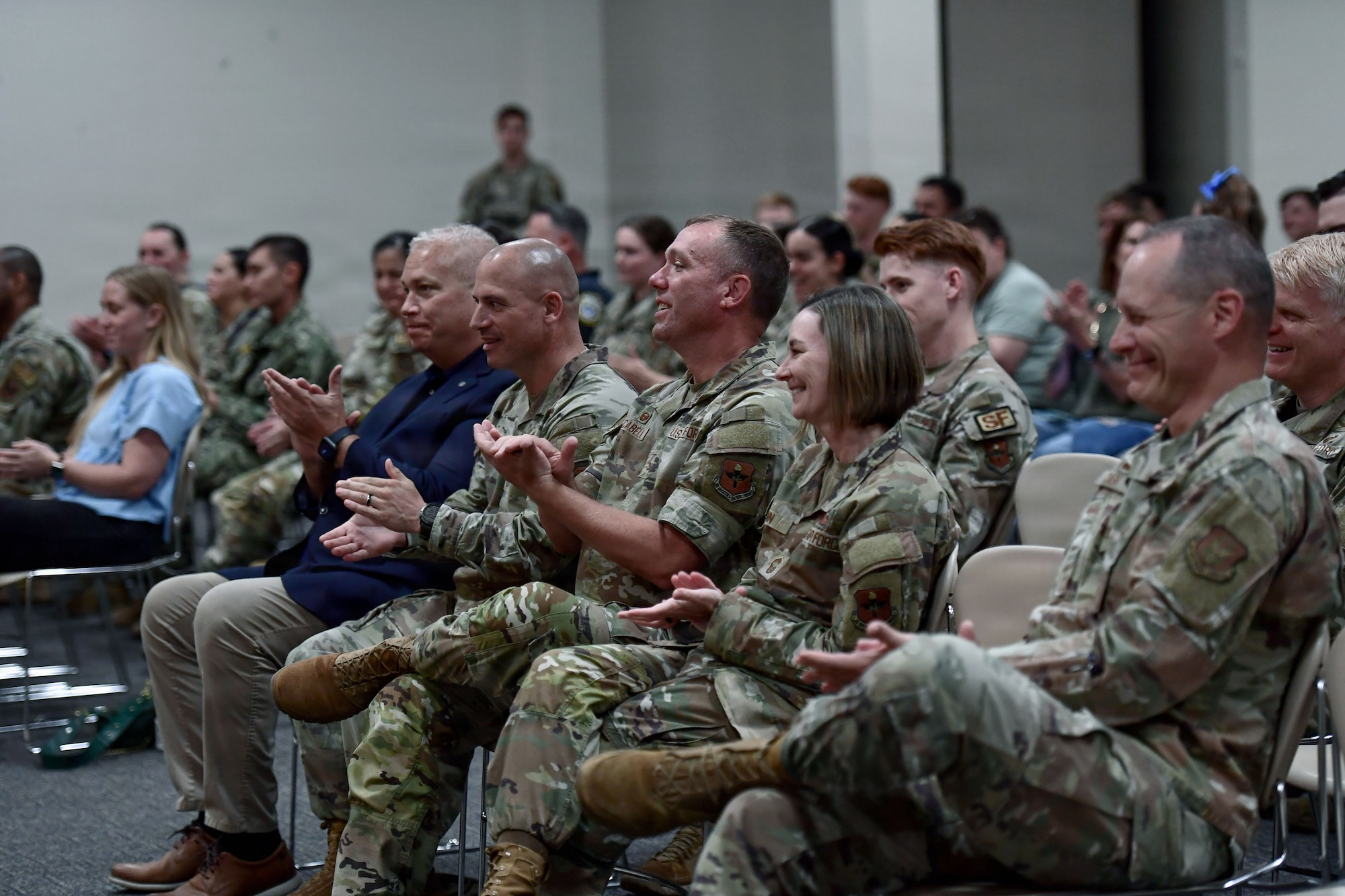 A crowd of military members applaud.