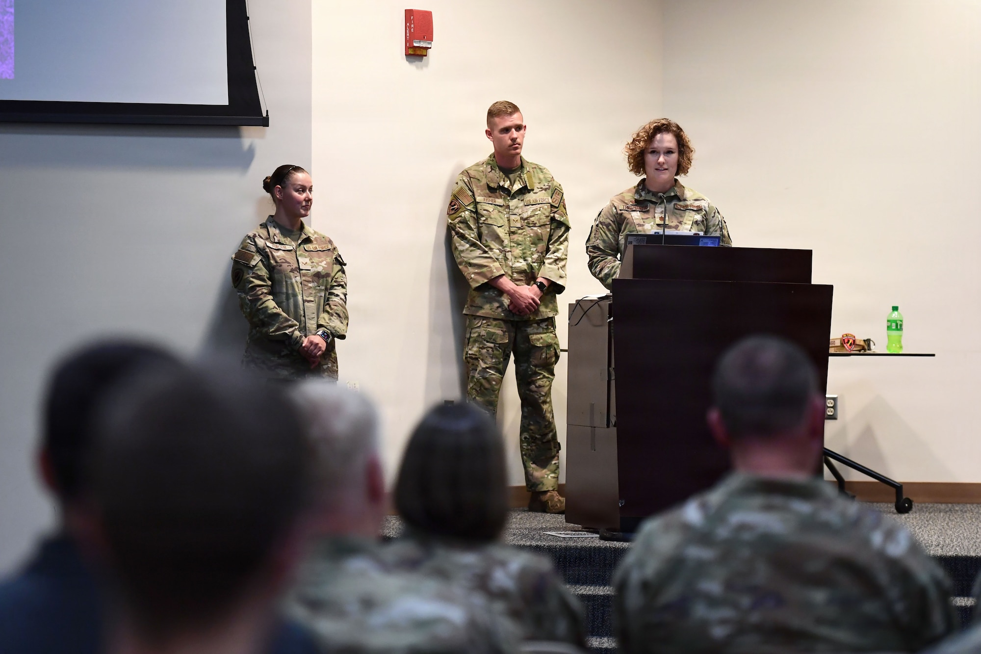A lady in military uniform speaks to a crowd from a podium.