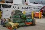 Bales of illicit drugs worth more than $19 million are stacked on a pier during a drug offload from USCGC Resolute (WMEC 620) at Base Miami Beach, Florida, April 23, 2026. The seized contraband was the result of three interdictions in the Caribbean Sea by the crew of the Coast Guard Cutter Tahoma and the crew of the USS Billings with an embarked Coast Guard law enforcement detachment. (U.S. Coast Guard photo by Petty Officer 3rd Class Reese Hindmarsh)