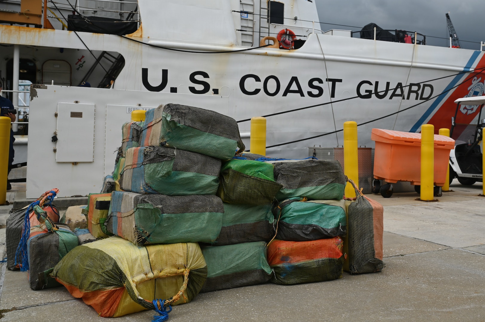 Bales of illicit drugs worth more than $19 million are stacked on a pier during a drug offload from USCGC Resolute (WMEC 620) at Base Miami Beach, Florida, April 23, 2026. The seized contraband was the result of three interdictions in the Caribbean Sea by the crew of the Coast Guard Cutter Tahoma and the crew of the USS Billings with an embarked Coast Guard law enforcement detachment. (U.S. Coast Guard photo by Petty Officer 3rd Class Reese Hindmarsh)