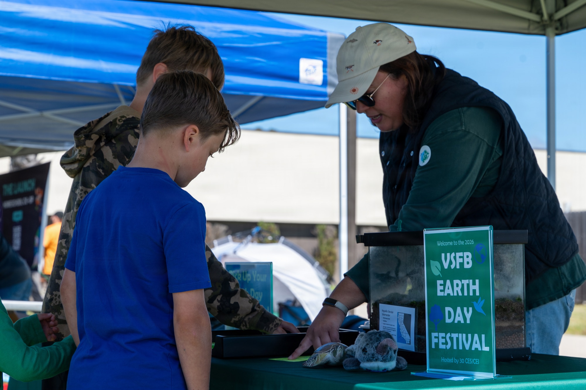 Three people attend an informational booth set up outside.