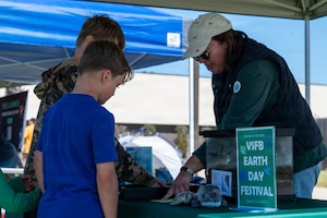 Three people attend an informational booth set up outside.