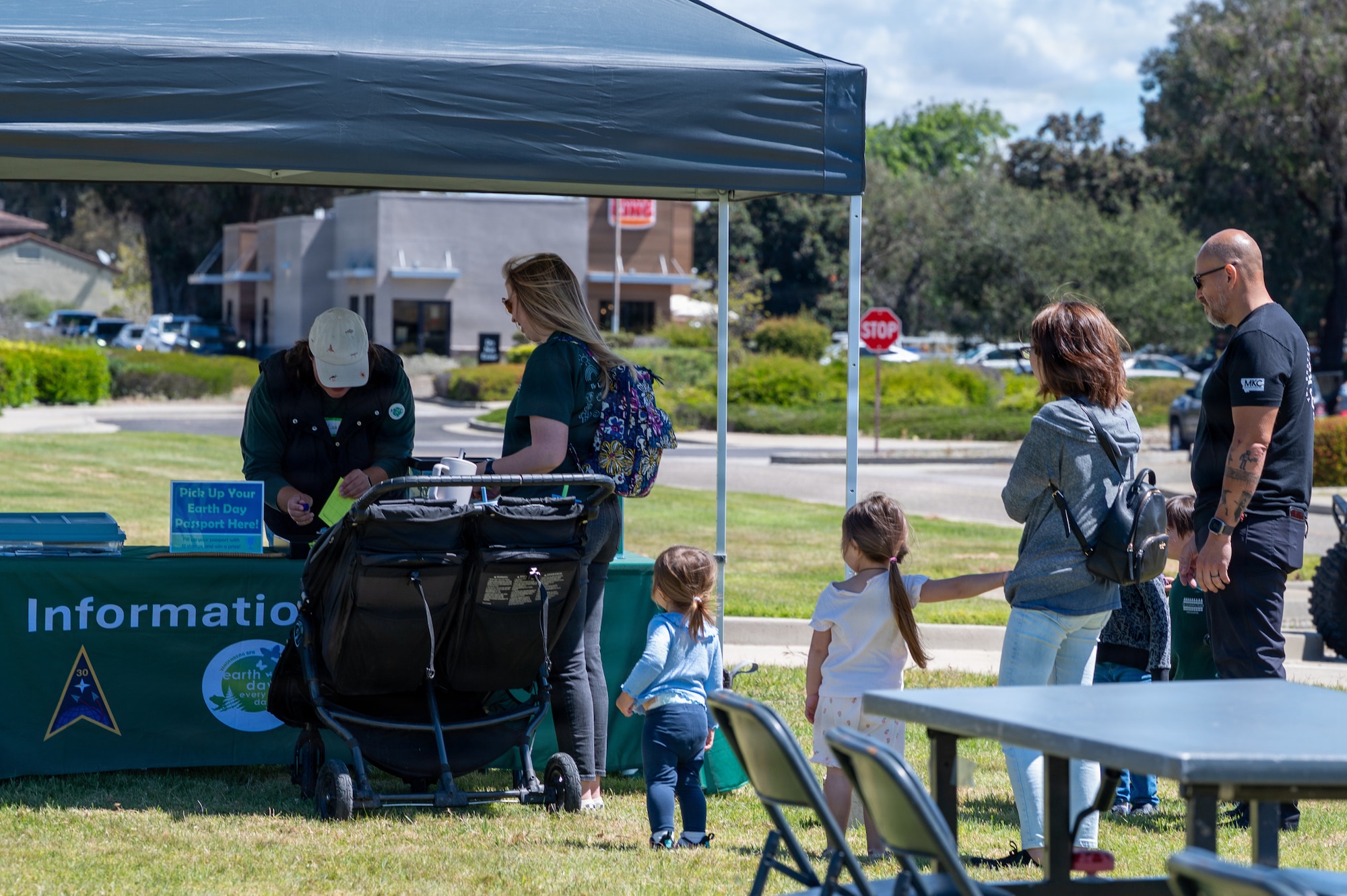 Vandenberg families and servicemembers gather outside the Vandenberg Library, and walk toward an informational booth on the grass.