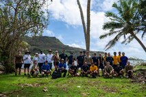 Sailors and civilians from Commander, Submarine Squadron 15 (CSS-15), pose for a group photo after participating in a beach cleanup following Super Typhoon Sinlaku. CSS-15 and other military commands across Guam are providing vital support to villages and civil authorities, strengthening crisis response and recovery efforts in the wake of Super Typhoon Sinlaku.