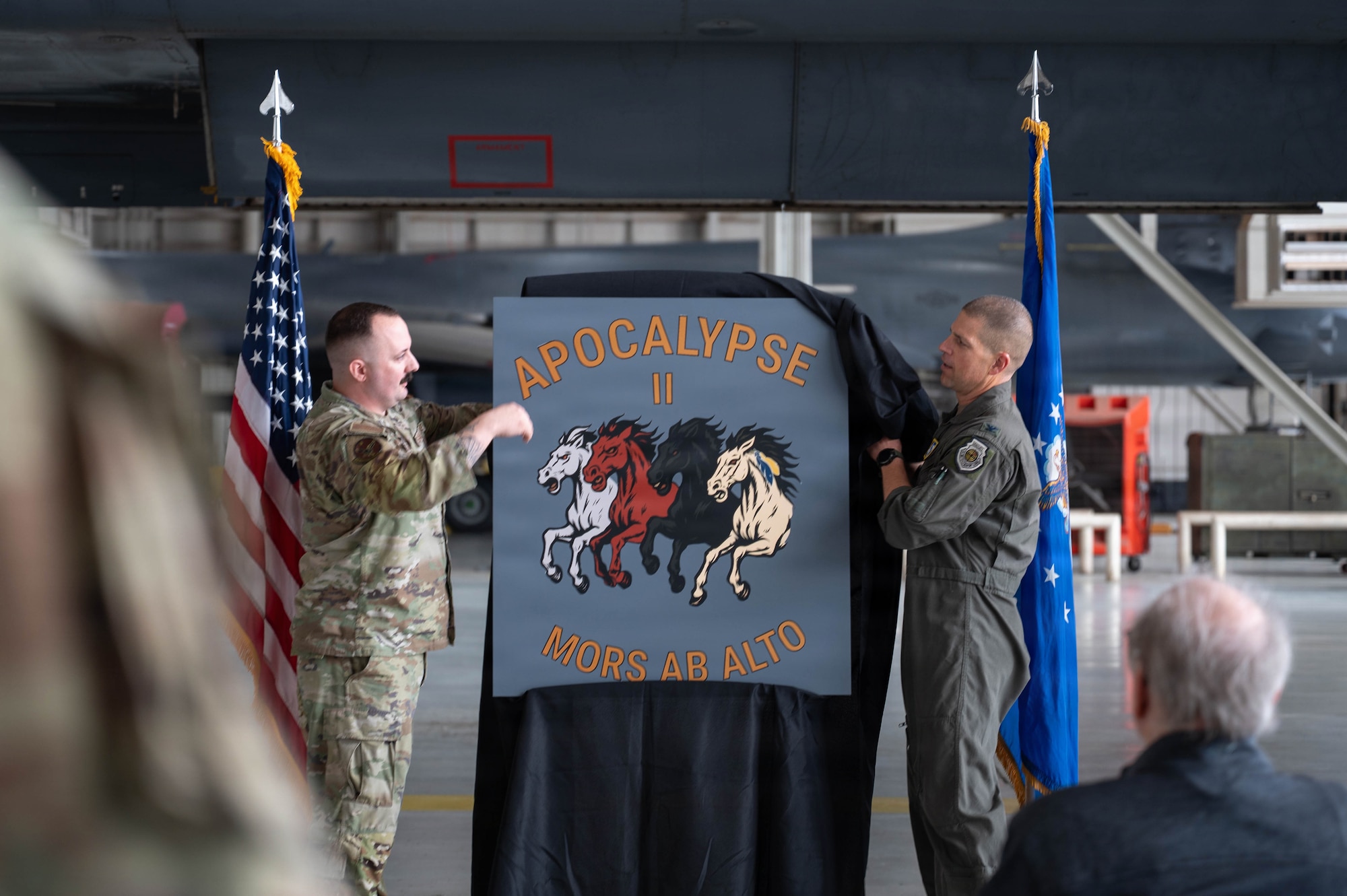 Airmen unveil a nose art design inside an airplane hangar