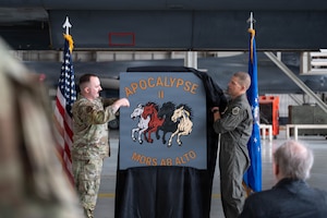 Airmen unveil a nose art design inside an airplane hangar